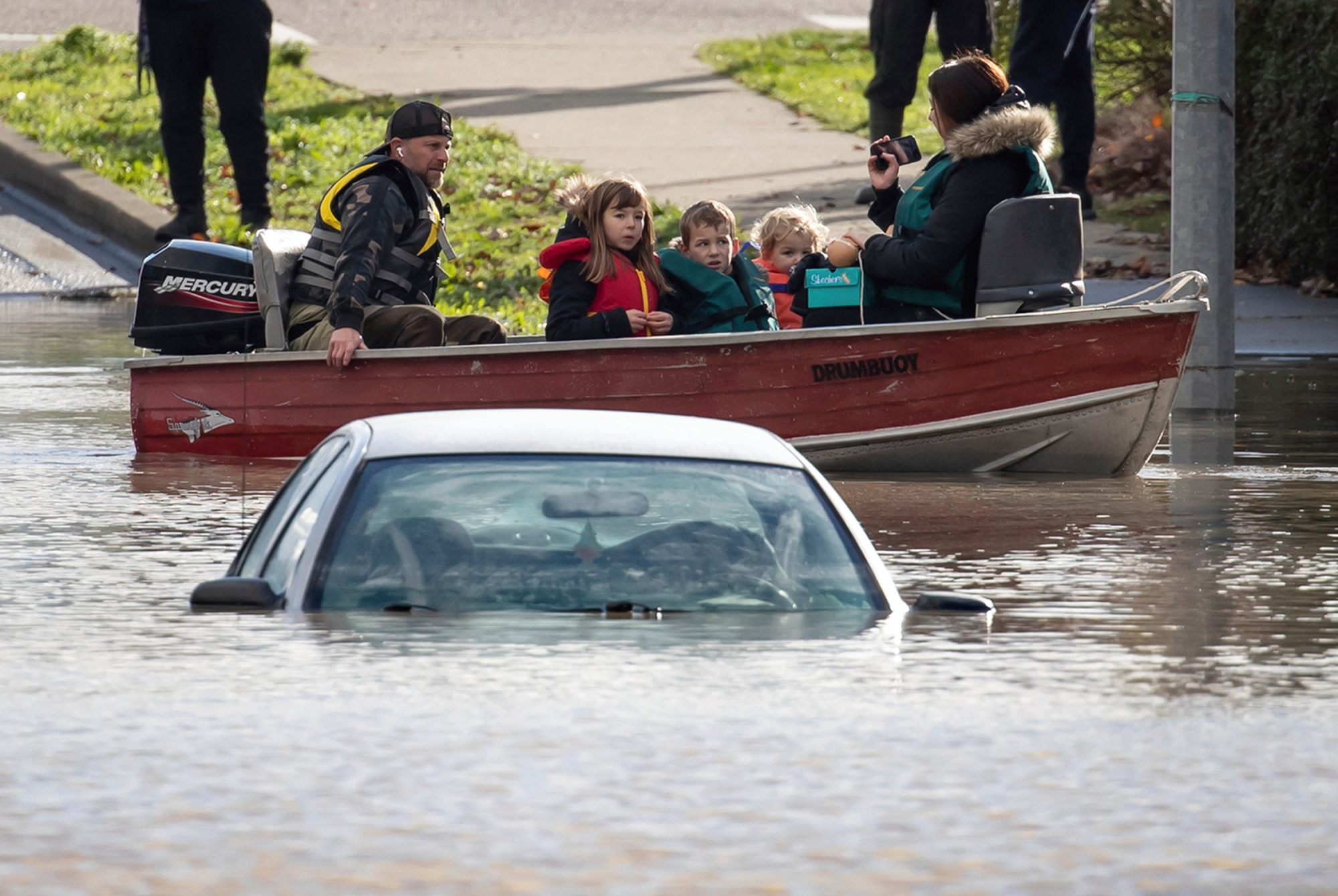 En volontär i båt evakuerar en familj som strandats av de enorma vattenmassorna