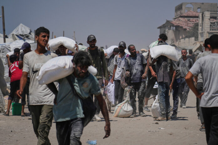 Palestinier bär mjöl som kommer från humanitär hjälp som nådde Gaza stad på söndagen